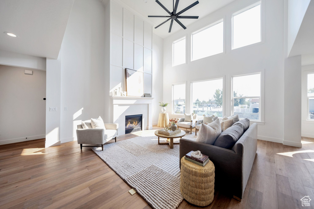 Living room featuring a high ceiling, light wood-type flooring, and ceiling fan