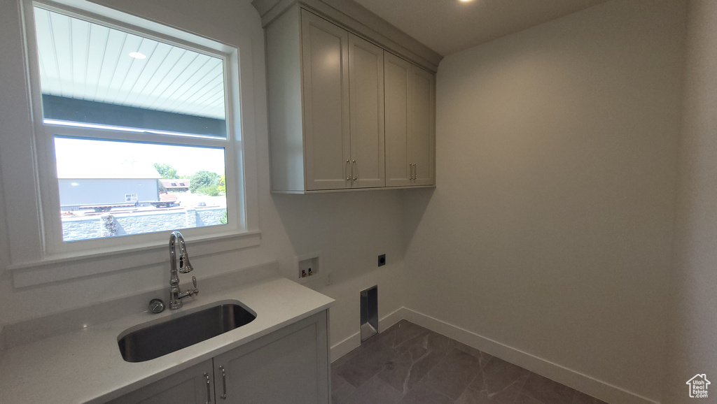 Clothes washing area featuring cabinets, washer hookup, hookup for an electric dryer, sink, and dark tile floors