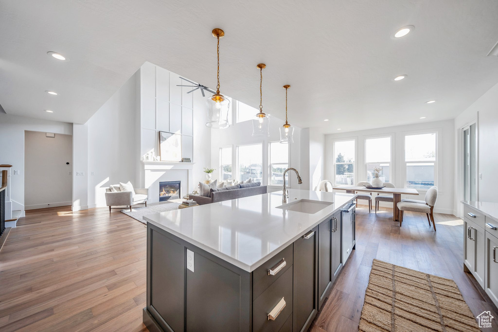 Kitchen featuring sink, a fireplace, a kitchen island with sink, and light hardwood / wood-style floors