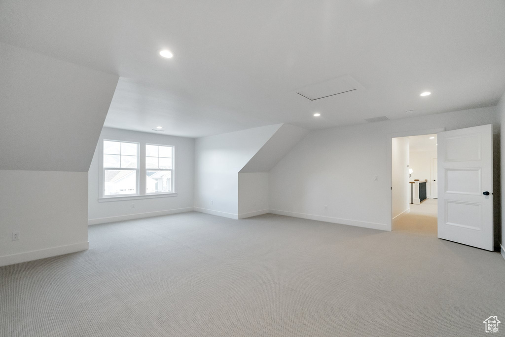 Additional living space featuring lofted ceiling and light carpet