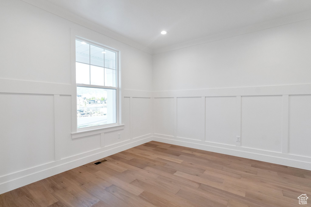 Unfurnished room with light hardwood / wood-style floors and crown molding