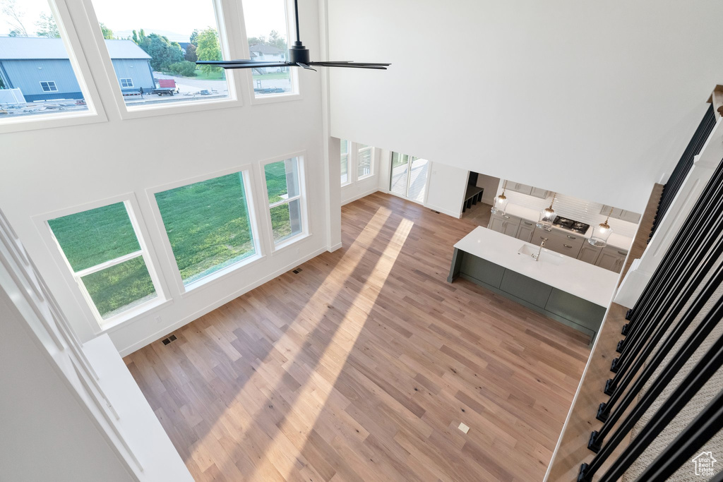 Unfurnished living room featuring a towering ceiling, wood-type flooring, and ceiling fan