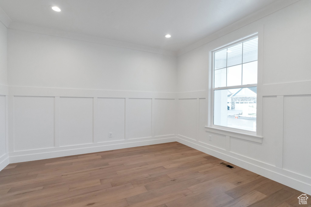 Spare room with a healthy amount of sunlight, light hardwood / wood-style floors, and crown molding