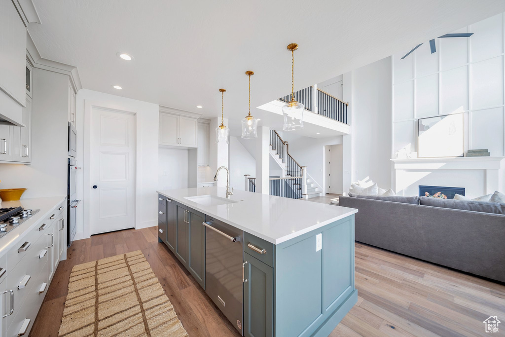 Kitchen featuring a kitchen island with sink, light hardwood / wood-style floors, hanging light fixtures, appliances with stainless steel finishes, and sink