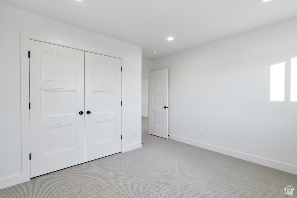 Unfurnished bedroom with light carpet and a closet