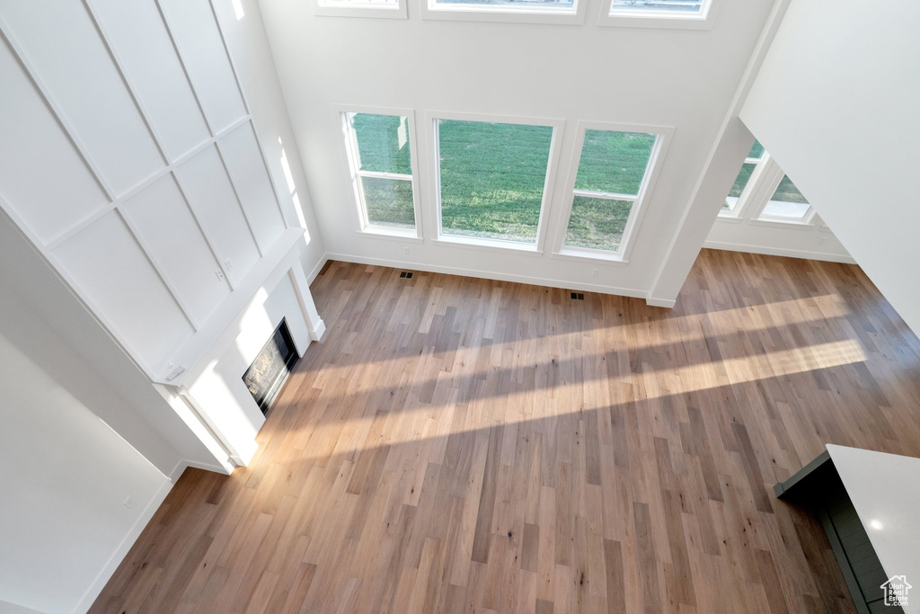 Unfurnished living room with a high ceiling, hardwood / wood-style flooring, and a fireplace