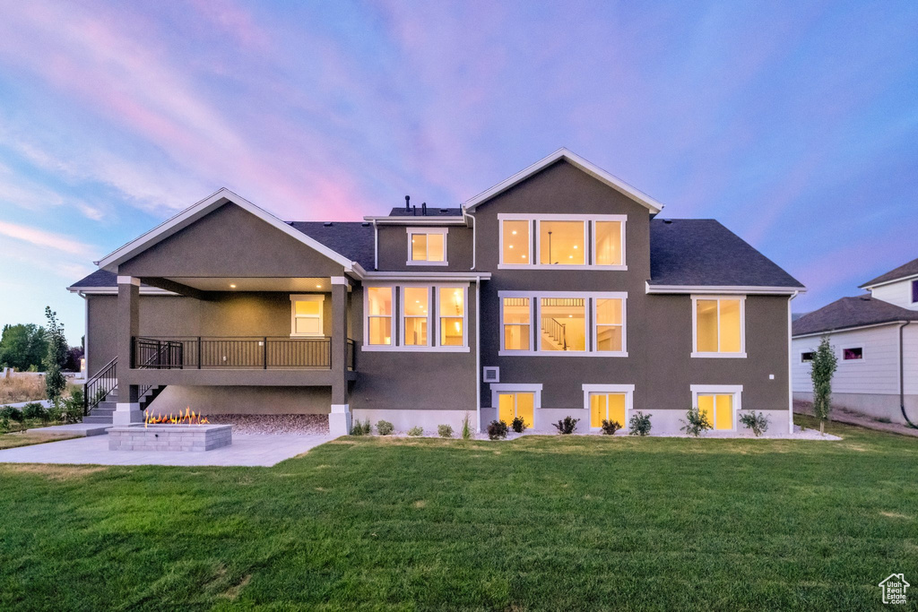 Back house at dusk with a lawn and a patio