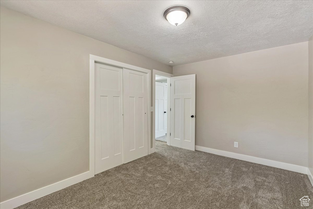 Unfurnished bedroom featuring carpet flooring, a closet, and a textured ceiling