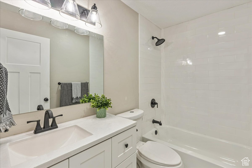 Full bathroom featuring tiled shower / bath, vanity, and toilet