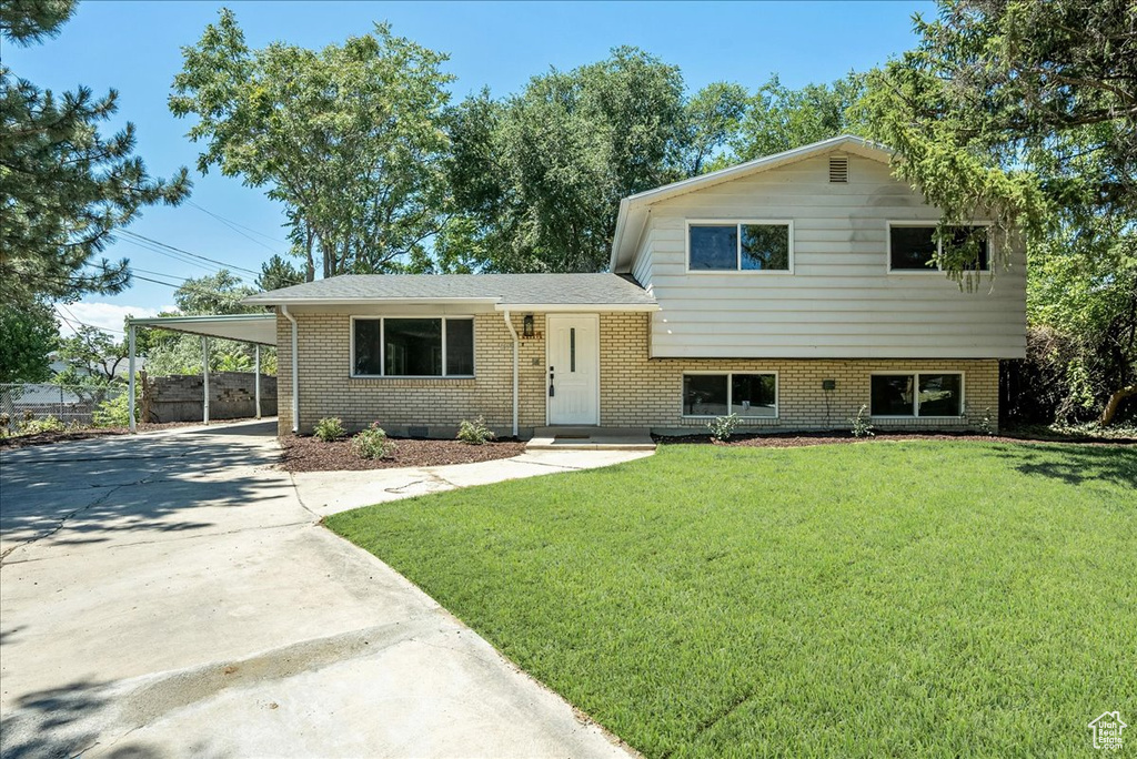 Tri-level home featuring a carport and a front lawn