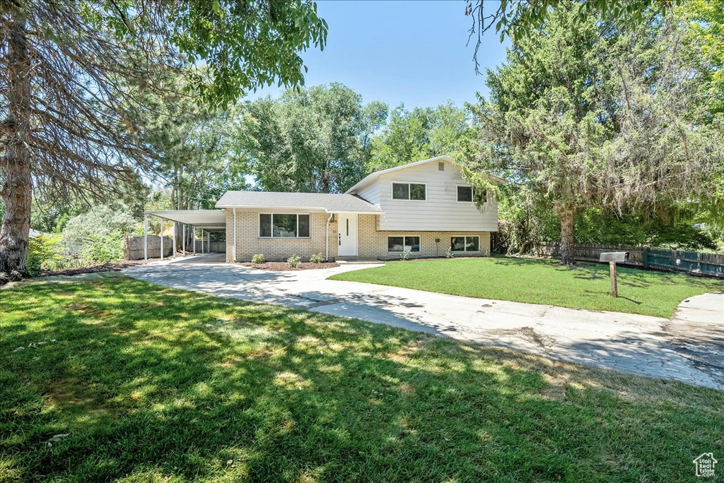 Tri-level home featuring a front lawn and a carport