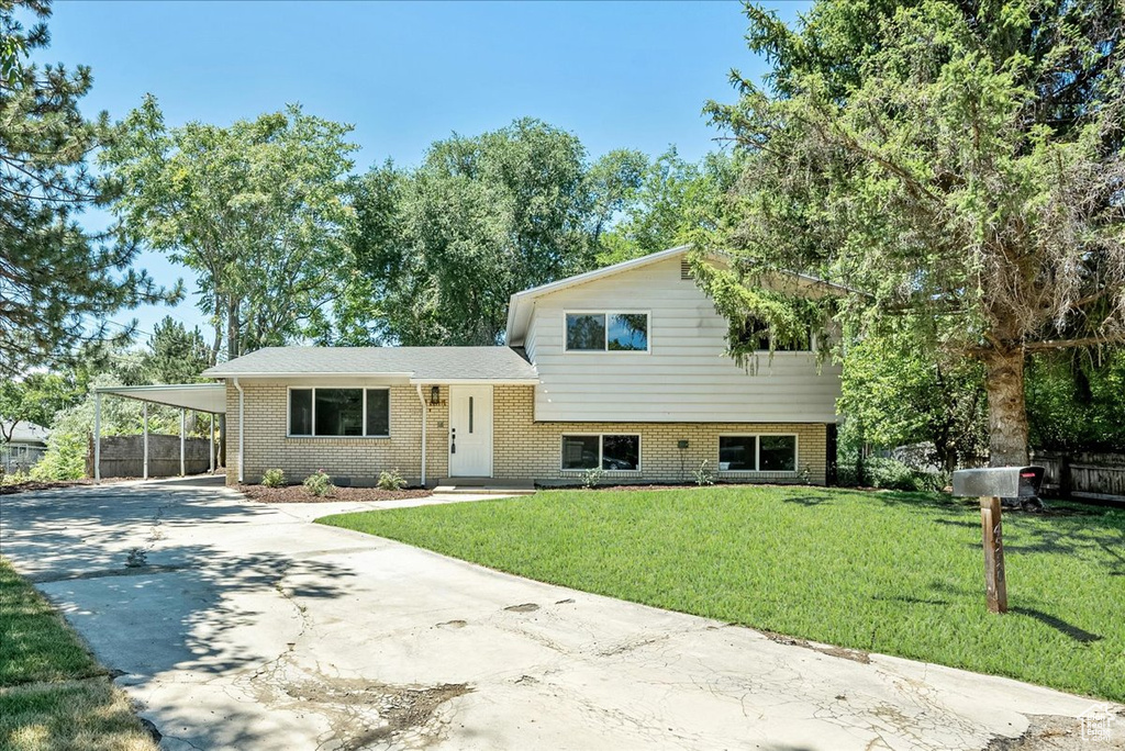 Tri-level home featuring a carport and a front lawn