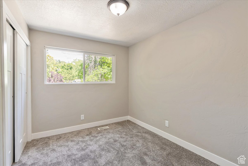 Carpeted spare room featuring a textured ceiling