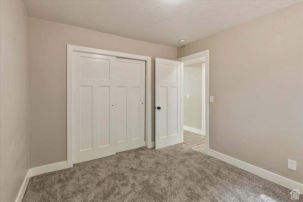 Unfurnished bedroom featuring a closet, carpet floors, and a textured ceiling