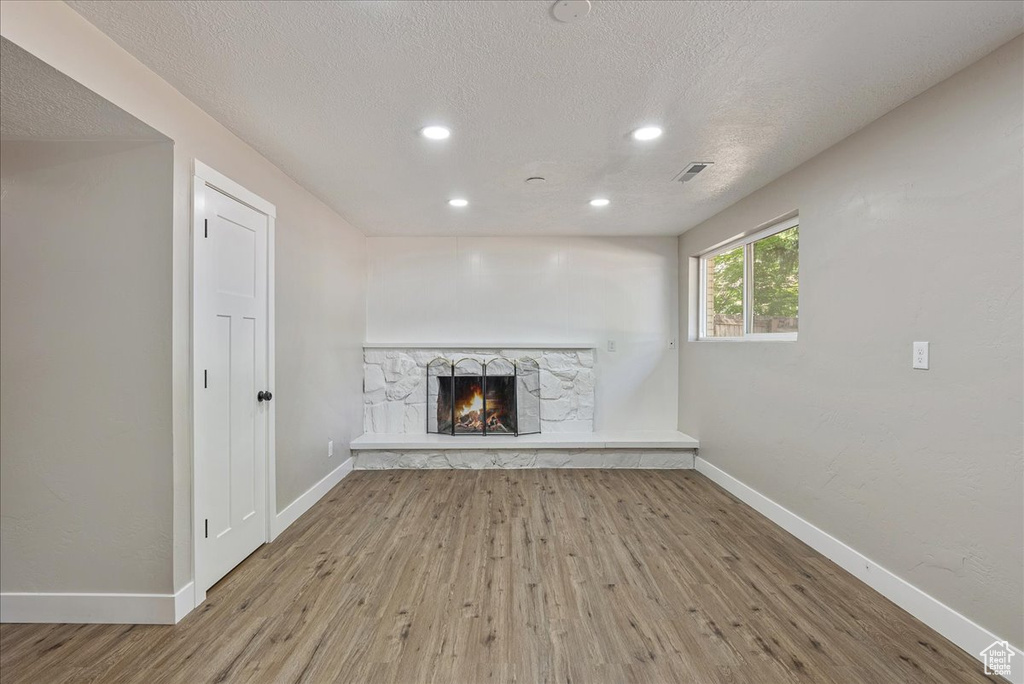 Unfurnished living room with a textured ceiling, a fireplace, and wood-type flooring