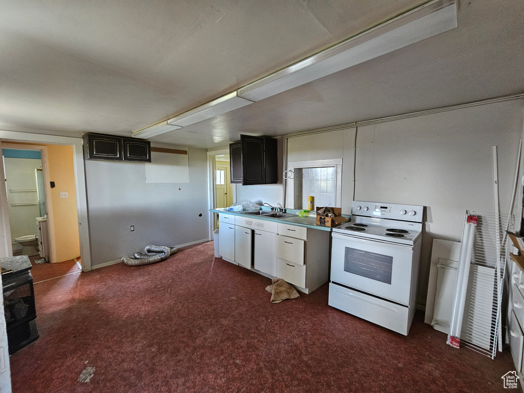 Kitchen featuring carpet flooring, sink, and white range with electric stovetop