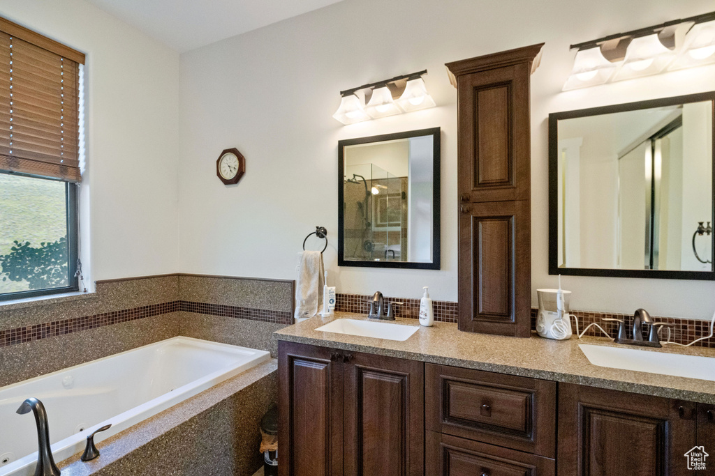 Bathroom with dual bowl vanity and tiled tub