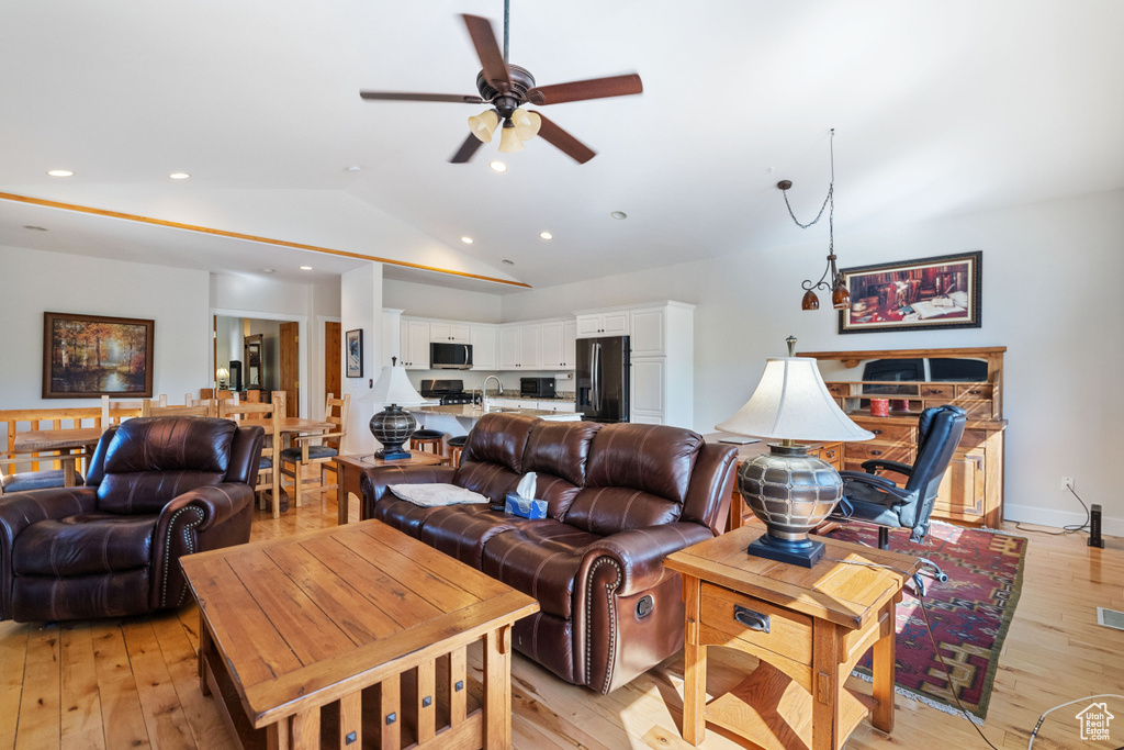 Living room with ceiling fan, light hardwood / wood-style floors, lofted ceiling, and sink