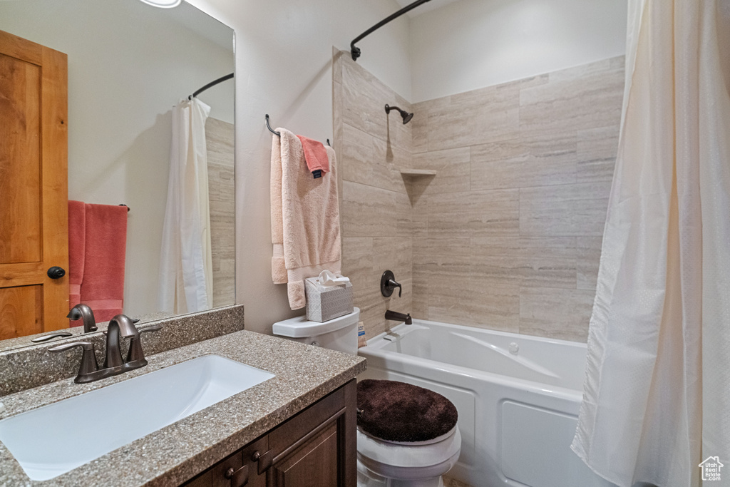 Full bathroom with toilet, shower / bath combo with shower curtain, and vanity