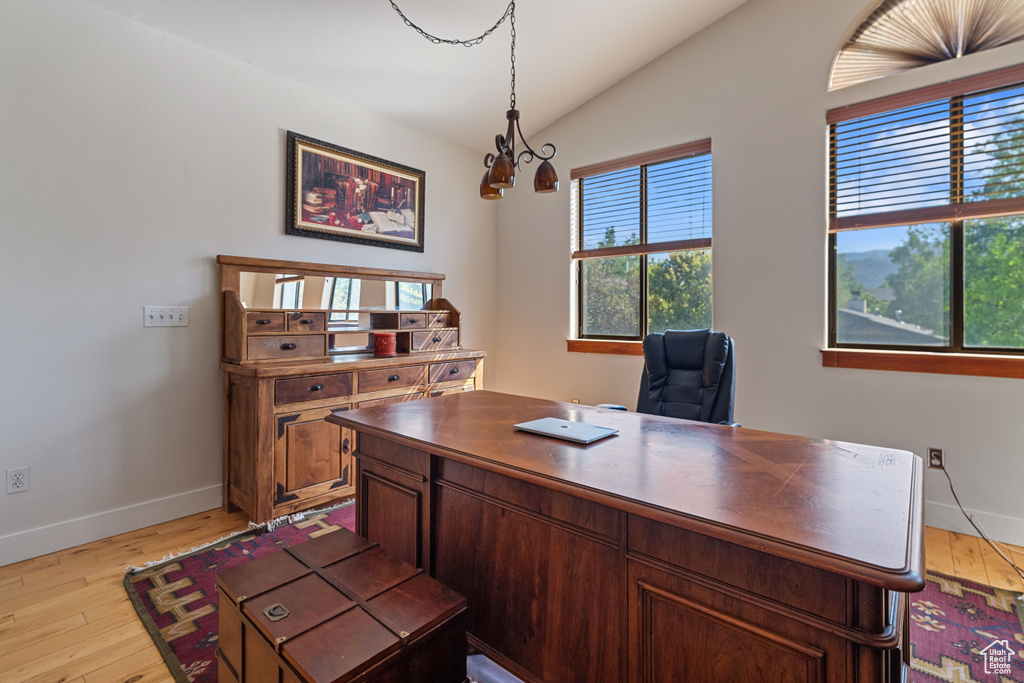 Office featuring light hardwood / wood-style flooring, lofted ceiling, and a notable chandelier