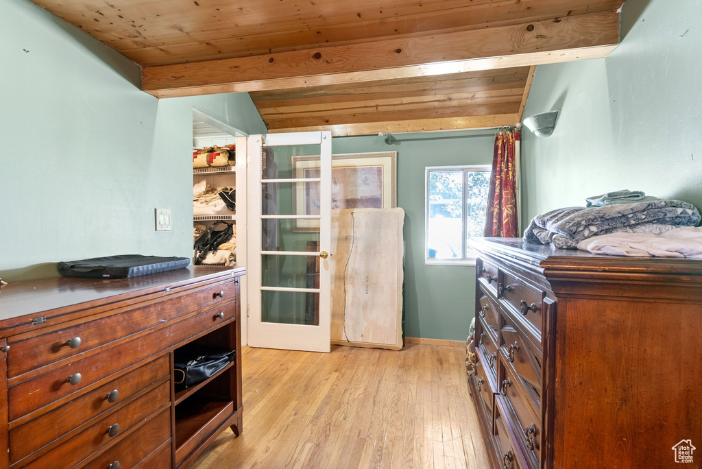 Bedroom featuring light hardwood / wood-style floors, vaulted ceiling with beams, and wooden ceiling