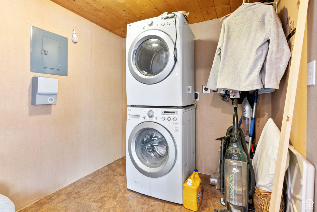 Clothes washing area with stacked washer and dryer and wood ceiling