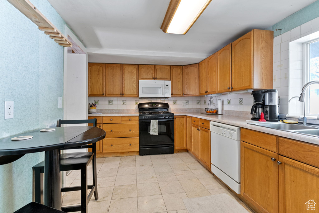 Kitchen with sink, tasteful backsplash, white appliances, and light tile floors