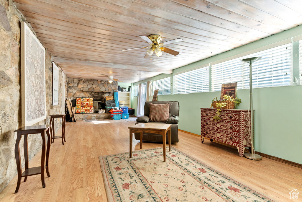 Sunroom / solarium with ceiling fan, a fireplace, and wood ceiling