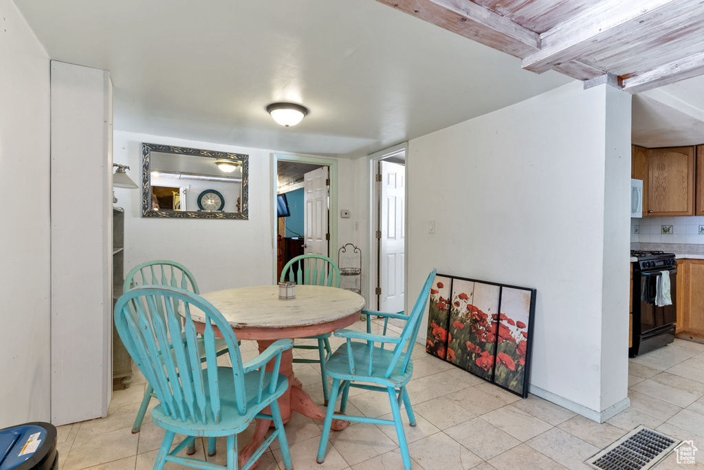 Dining area featuring beamed ceiling and light tile floors