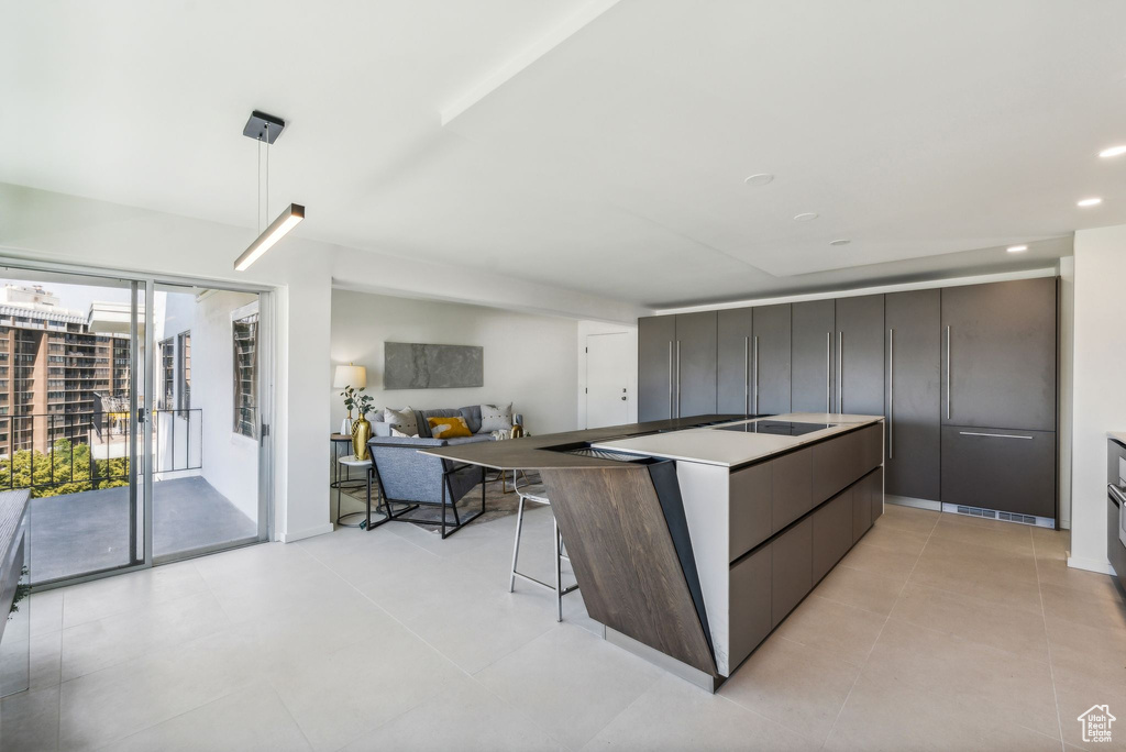 Kitchen with a kitchen bar, black electric cooktop, and light tile flooring