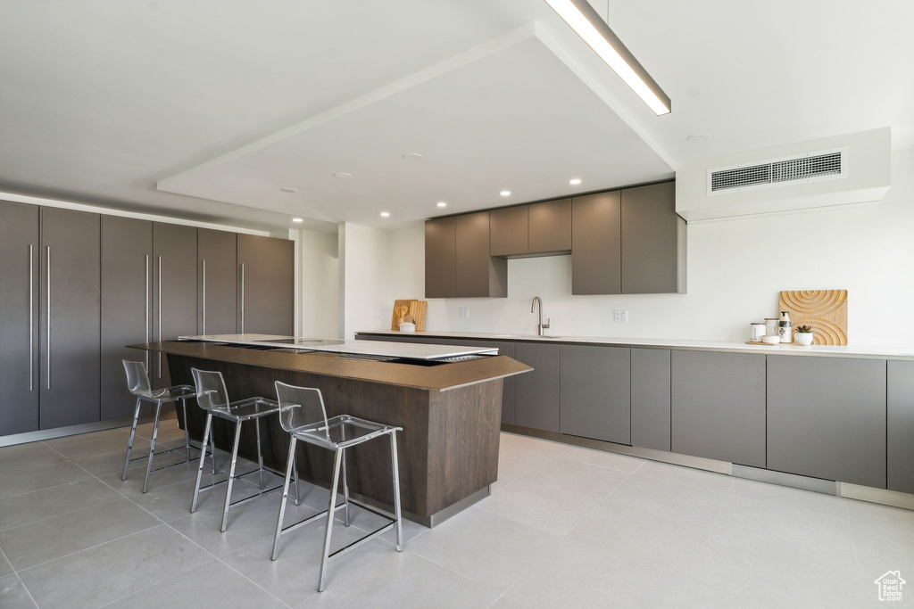 Kitchen with sink, a breakfast bar, light tile floors, and a kitchen island