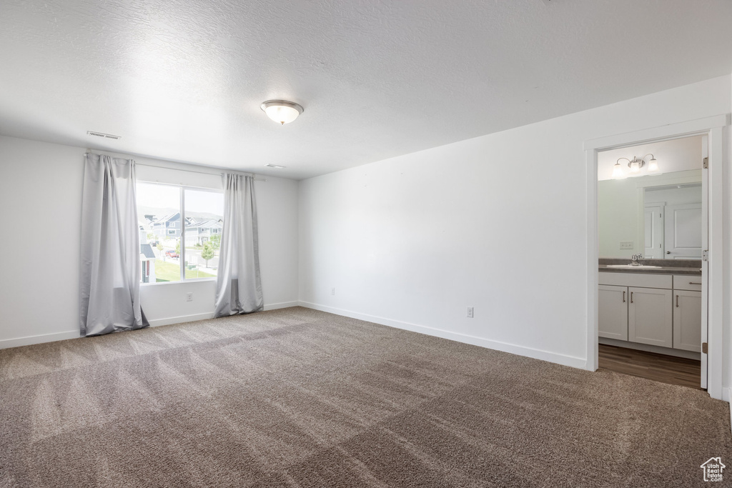 Unfurnished bedroom with ensuite bathroom, light carpet, and sink