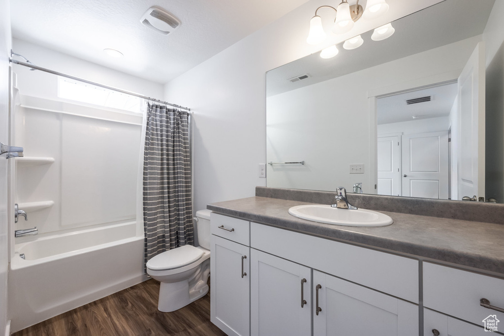 Full bathroom with vanity with extensive cabinet space, toilet, hardwood / wood-style flooring, and shower / tub combo with curtain