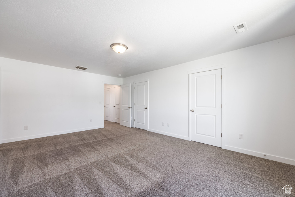 Unfurnished bedroom with dark carpet