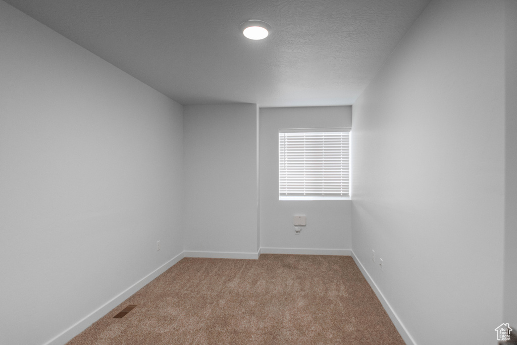 Carpeted spare room featuring a textured ceiling