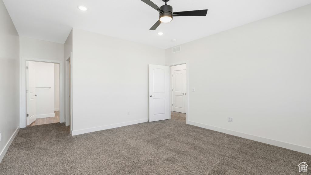 Unfurnished bedroom with dark colored carpet and ceiling fan