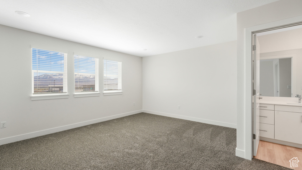 Unfurnished bedroom with sink, ensuite bath, and wood-type flooring