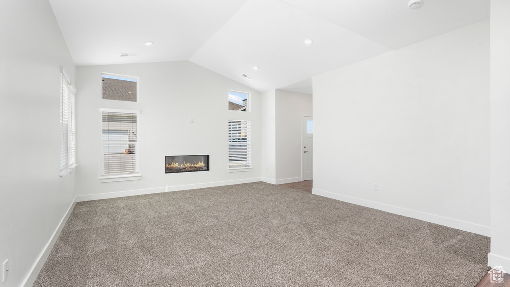 Unfurnished living room with carpet flooring and lofted ceiling