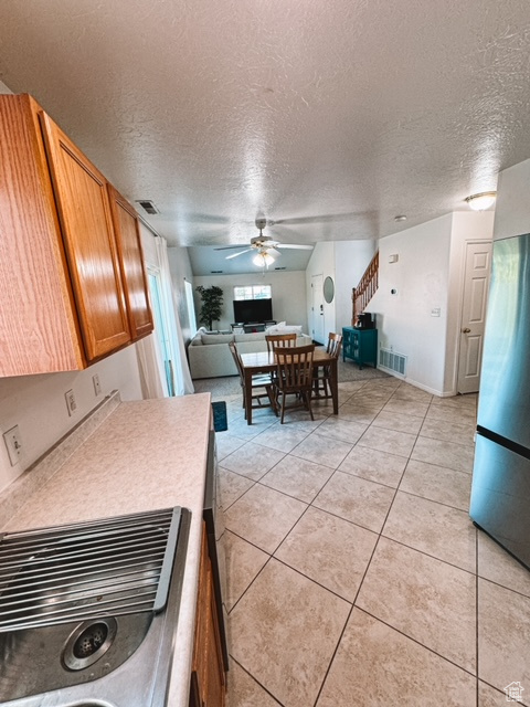 Kitchen featuring sink, a textured ceiling, light tile flooring, and ceiling fan