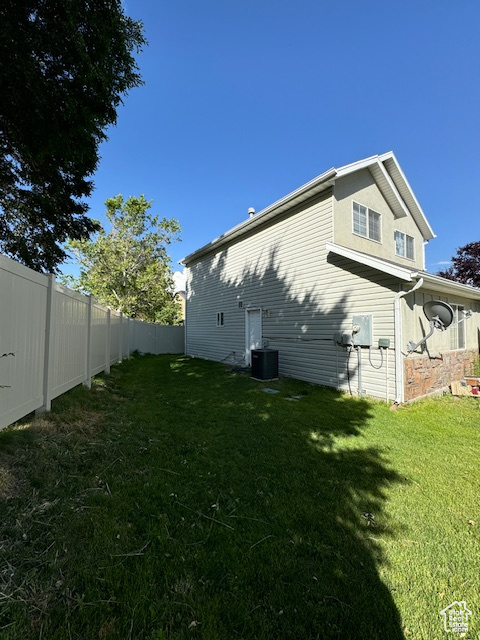 Rear view of house featuring a lawn and central air condition unit