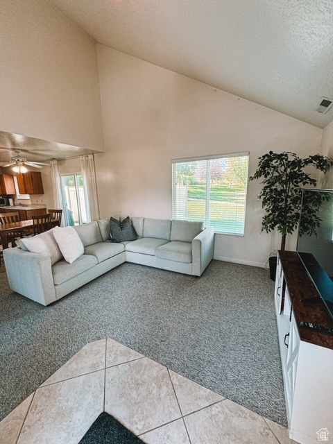 Living room featuring high vaulted ceiling, ceiling fan, and carpet floors