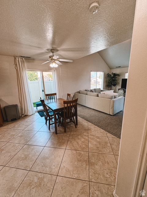 Dining room with light tile floors, a wealth of natural light, ceiling fan, and vaulted ceiling