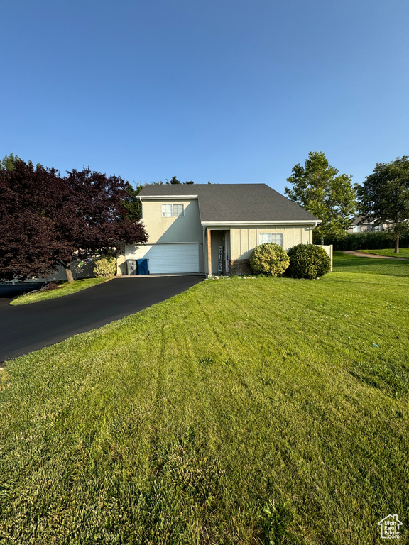 View of front of home with a garage and a front lawn