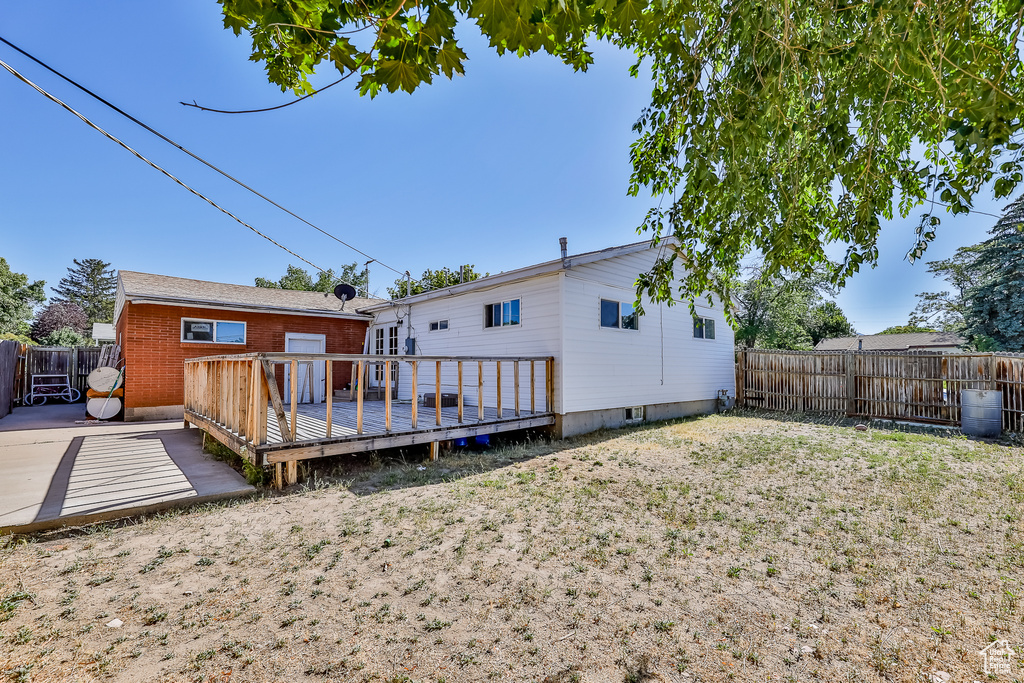 Rear view of house with a yard and a wooden deck