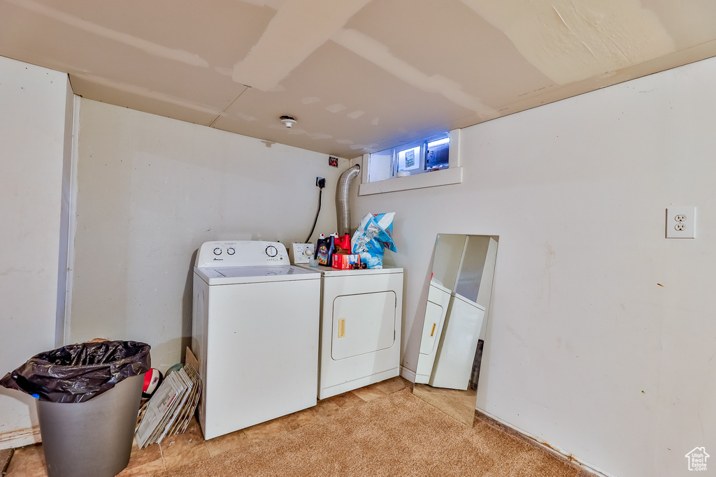 Clothes washing area featuring washing machine and dryer and light carpet