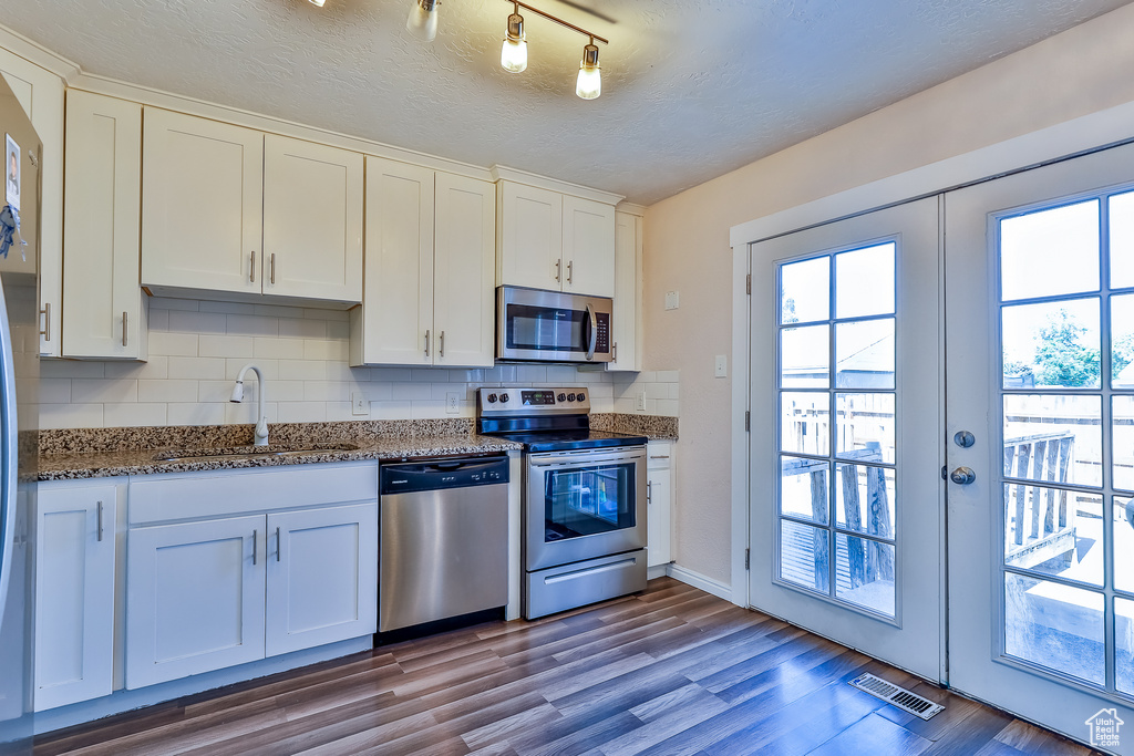 Kitchen featuring decorative backsplash, rail lighting, appliances with stainless steel finishes, and sink