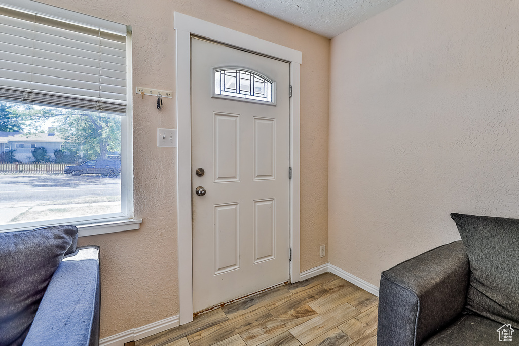 Foyer entrance with a textured ceiling and light hardwood / wood-style floors