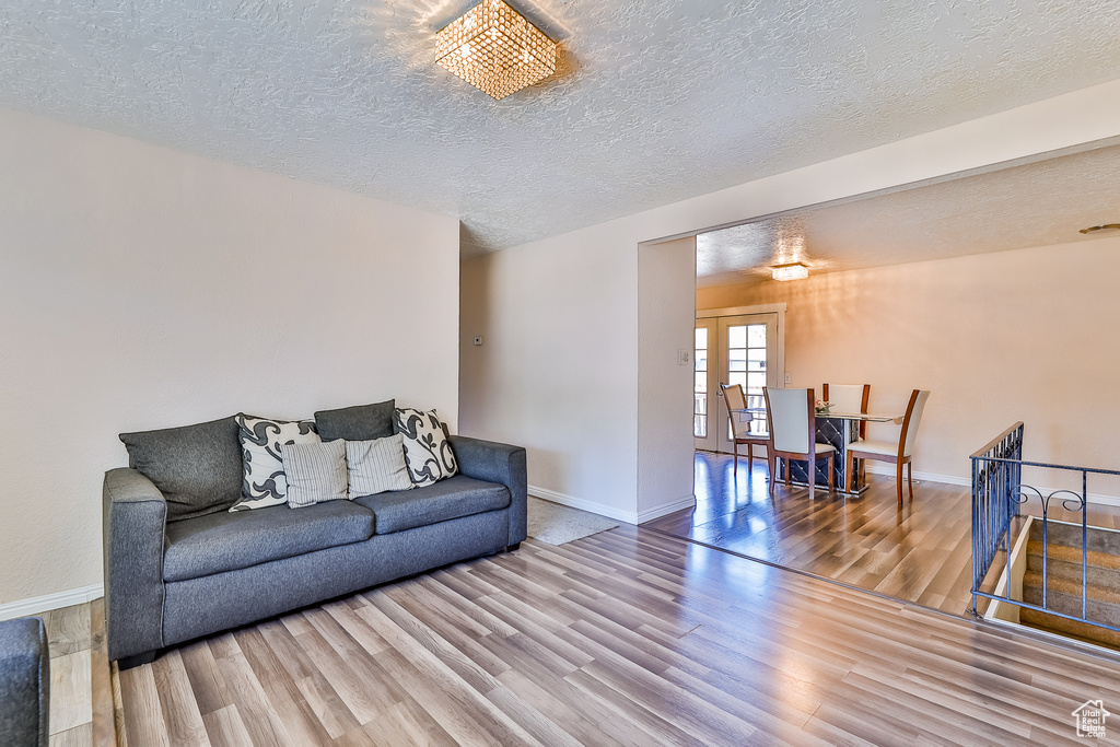 Living room with an inviting chandelier, a textured ceiling, and hardwood / wood-style flooring