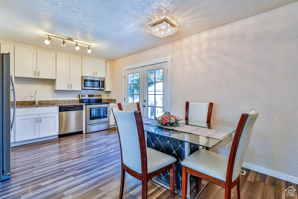 Dining area with hardwood / wood-style flooring, sink, french doors, a textured ceiling, and track lighting