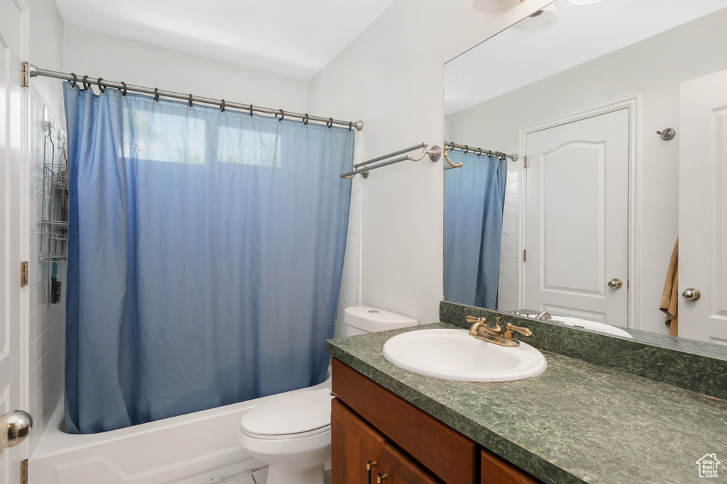 Full bathroom featuring shower / bath combination with curtain, toilet, and vanity